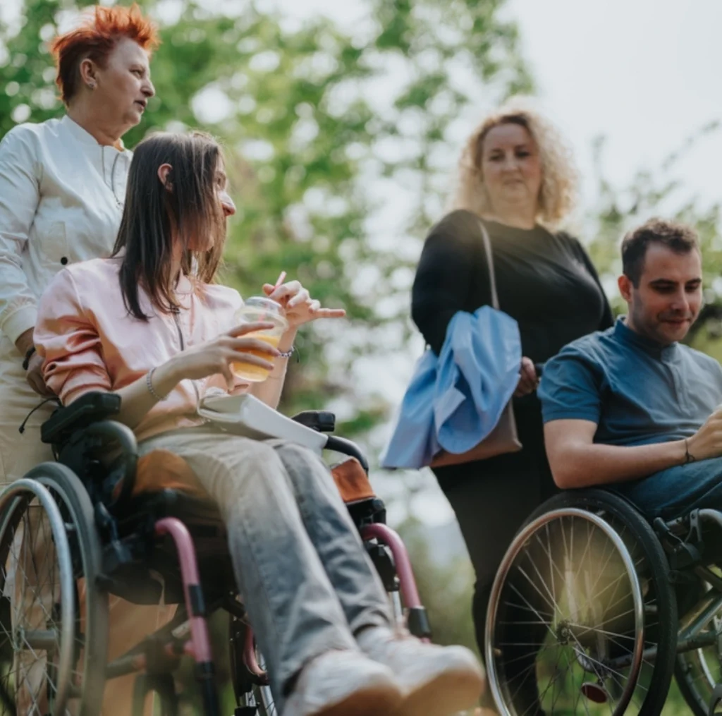 two disabled persons with caretakers in a park