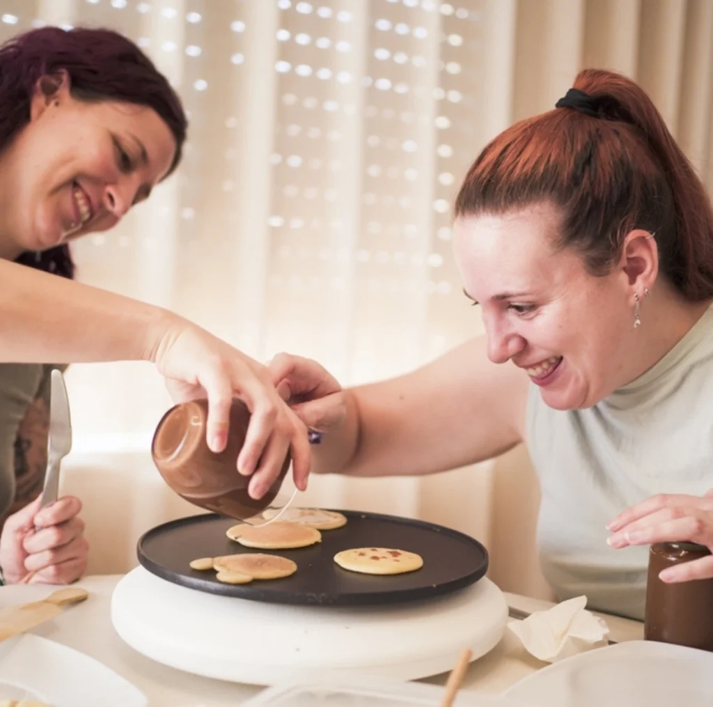 carer helping disabled woman in cooking in disability support home